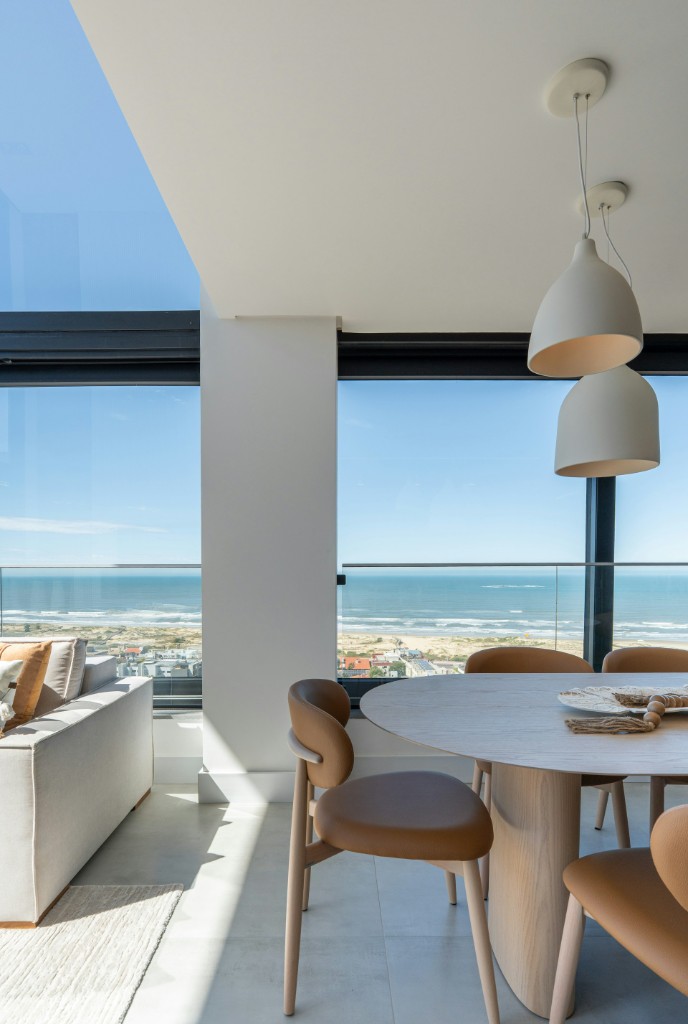 Sunlit living space looking out over a beach and the ocean